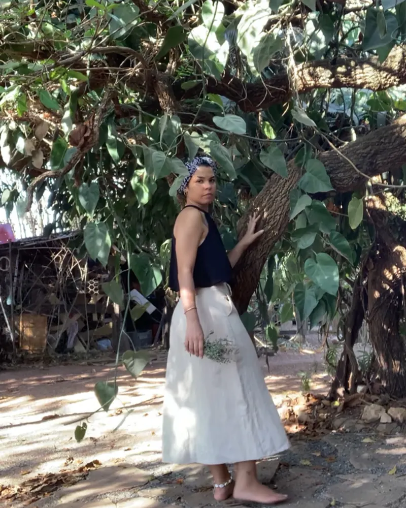 Ana Carol entre as plantas, segurando um ramo